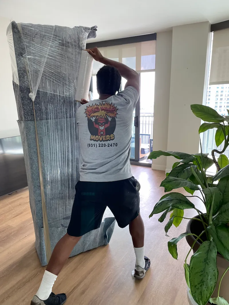 DynaMight Movers crew member shrink-wrapping a mattress before a Florida move.